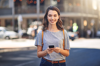 Buy stock photo Cropped portrait of an attractive young woman sending text messages while spending her day out in the city