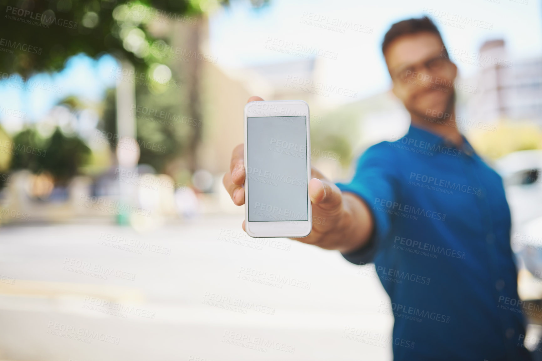Buy stock photo Shot of a man showing his cellphone while standing outside