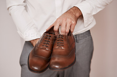 Buy stock photo Cropped shot of an unrecognizable bridegroom holding the shoes he's going to wear in a dressing room