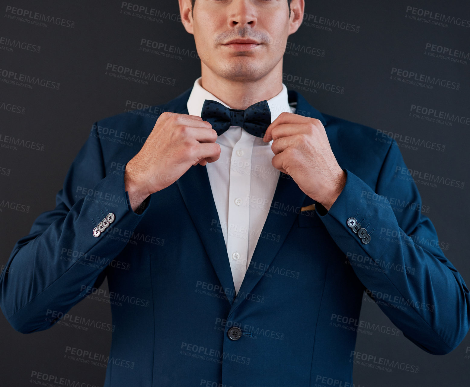 Buy stock photo Cropped shot of an unrecognizable bridegroom adjusting his bowtie in preparation for his wedding