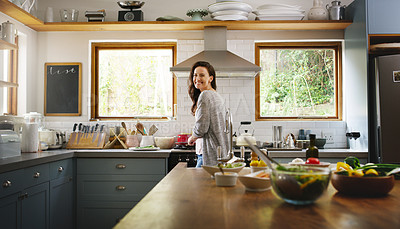 Buy stock photo Portrait of an attractive young woman smiling while cooking in her kitchen at home