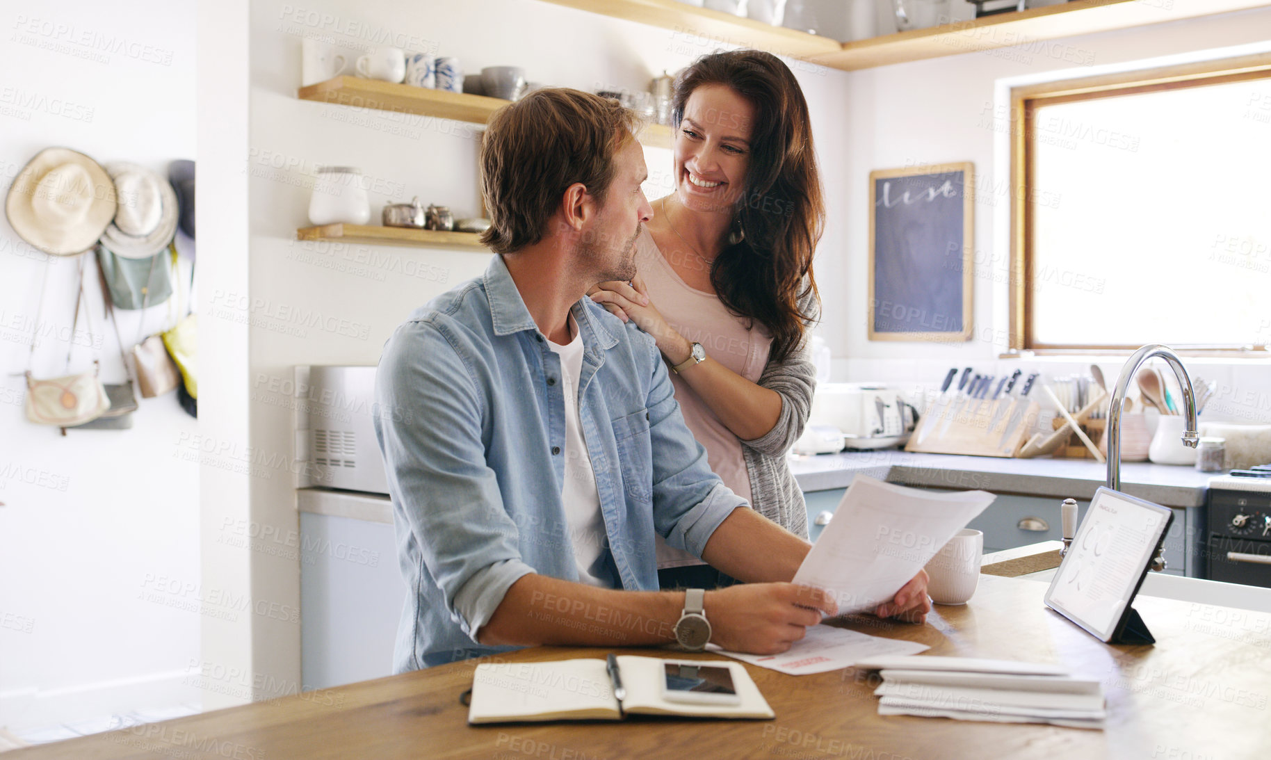 Buy stock photo Cropped shot of an affectionate young woman smiling at her husband while going through their budget at home