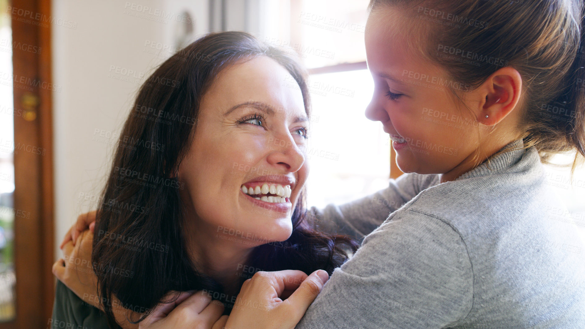 Buy stock photo Cropped shot of an affectionate young mother smiling at her daughter while spending time with her at home
