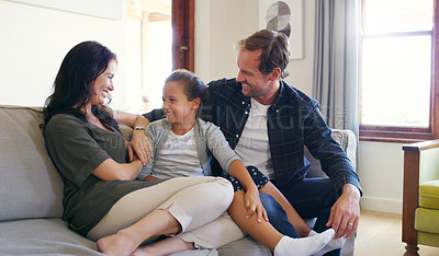 Buy stock photo Cropped shot of two affectionate young parents spending time with their daughter in their living room at home