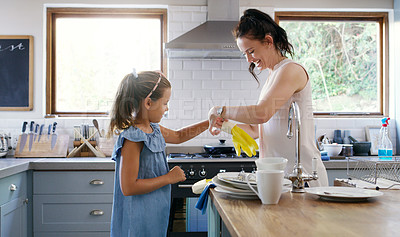 Buy stock photo Cropped shot of an affectionate young mother helping her daughter to put on rubber gloves while doing the dishes at home