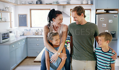 Buy stock photo Cropped shot of two affectionate young parents spending time with their kids in the kitchen at home