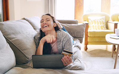 Buy stock photo Full length shot of an attractive young woman looking ecstatic while shopping online using a digital tablet in her living room