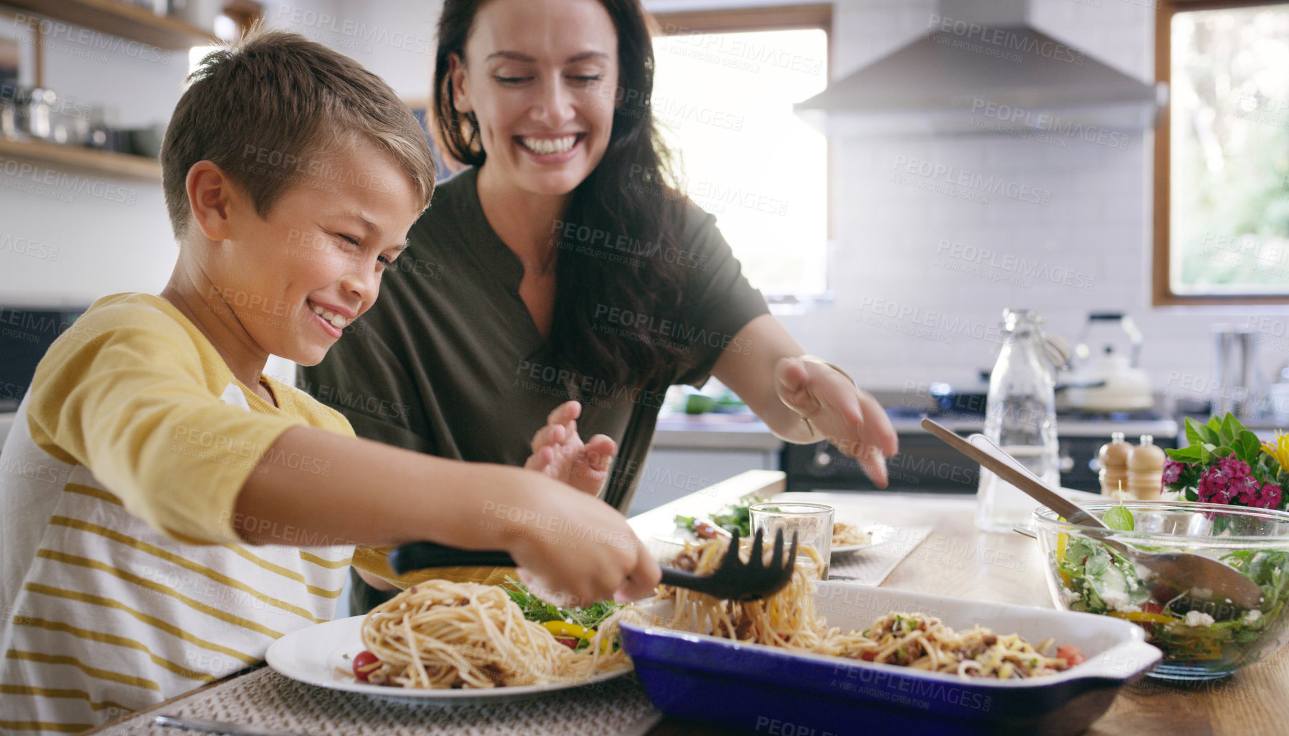Buy stock photo Cropped shot of an affectionate young mother serving her son during a meal on their kitchen table
