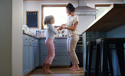 Buy stock photo Full length shot of an affectionate young mother dancing with her daughter in their kitchen at home