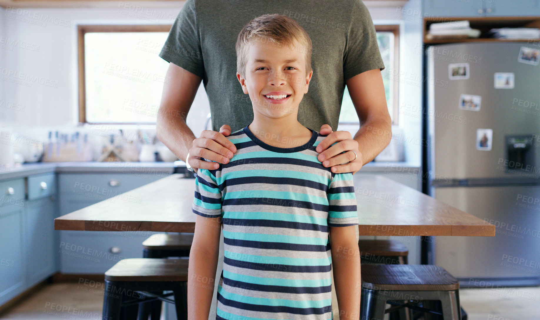 Buy stock photo Cropped shot of an unrecognizable young father holding his son while standing in their kitchen at home