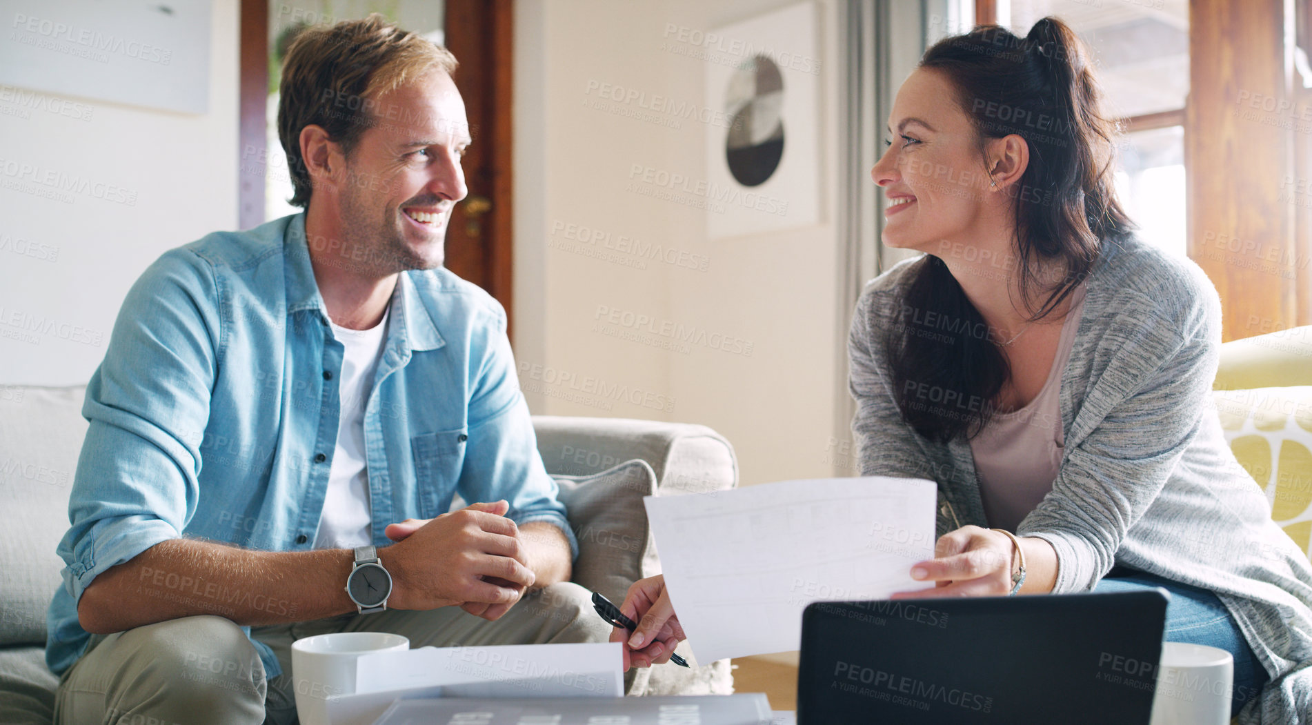 Buy stock photo Cropped shot of an affectionate young couple smiling at each other while going through their budget at home