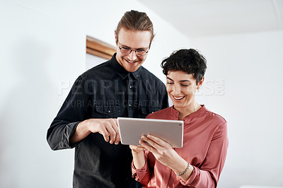Buy stock photo Cropped shot of two young businesspeople standing together in the office and working on a tablet