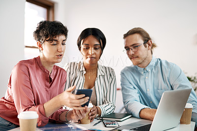Buy stock photo Cropped shot of a diverse group of businesspeople sitting together and using technology during a meeting in the office