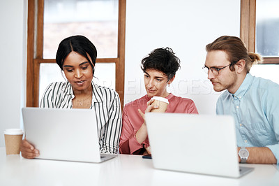 Buy stock photo Cropped shot of a diverse group of businesspeople sitting together and using their laptops during a meeting in the office
