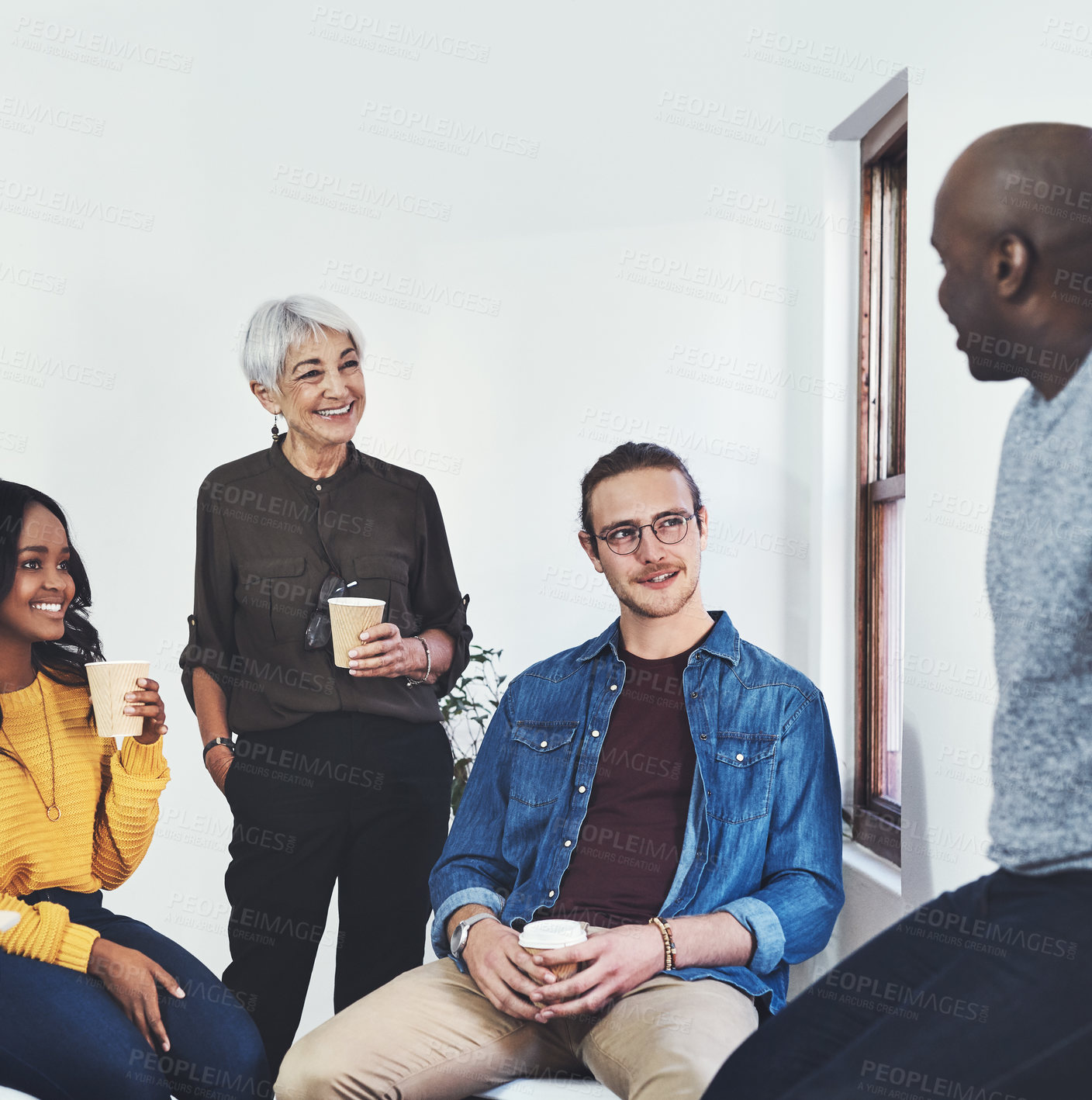 Buy stock photo Cropped shot of a group of cheerful businesspeople having a discussion while drinking coffee inside of the office
