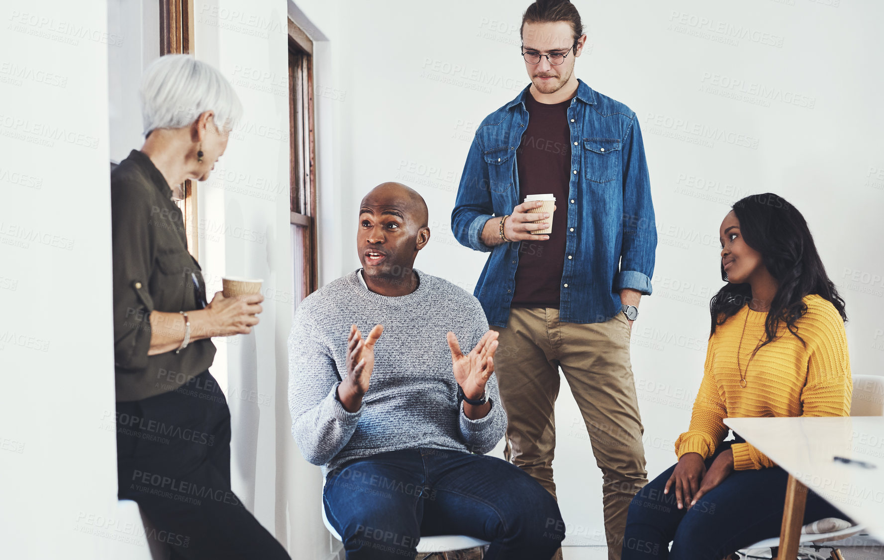 Buy stock photo Cropped shot of a group of cheerful businesspeople having a discussion while drinking coffee inside of the office
