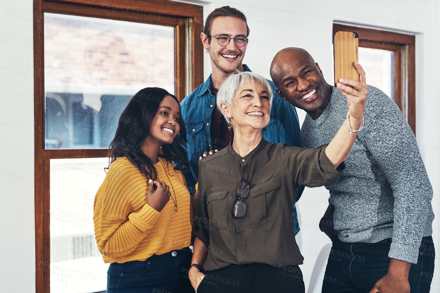 Buy stock photo Cropped shot of a group of cheerful businesspeople taking a self portrait together with a cellphone inside of the office