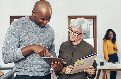 Buy stock photo Cropped shot of two confident businesspeople browsing on a digital tablet together inside of the office during the day