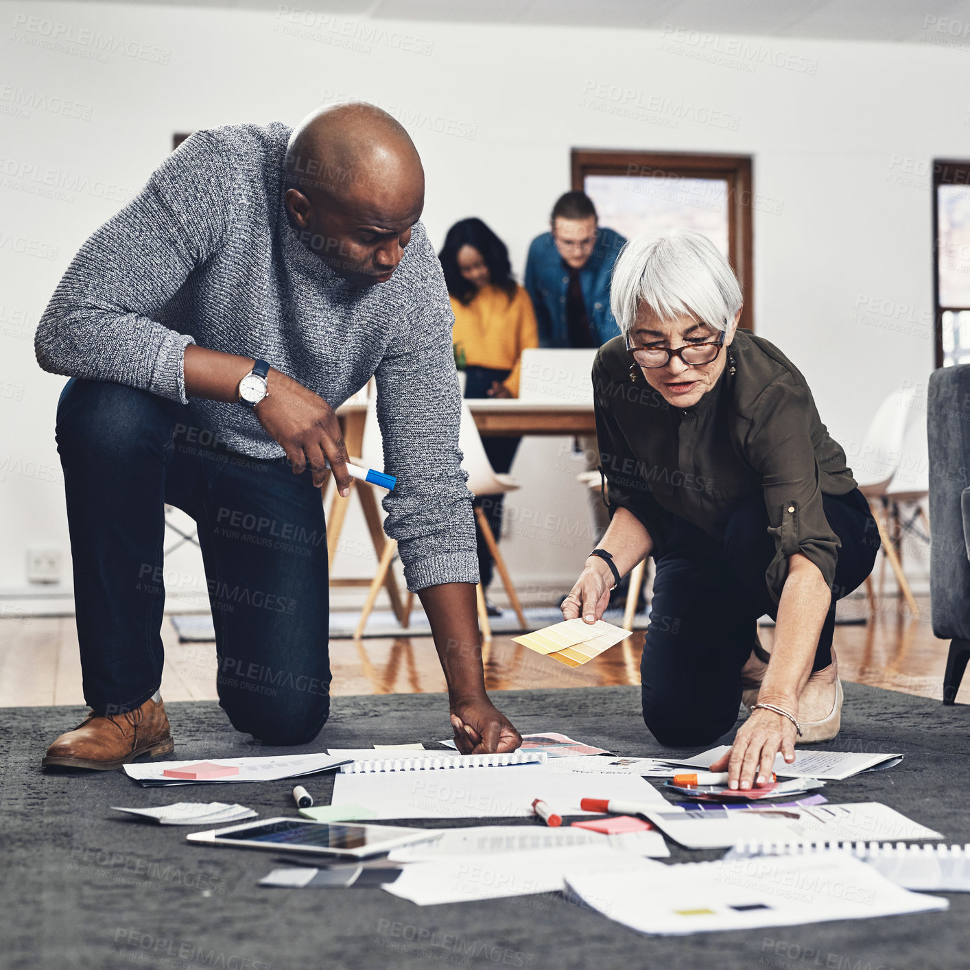 Buy stock photo Full length shot of two businesspeople looking over paperwork while working on the floor of their office