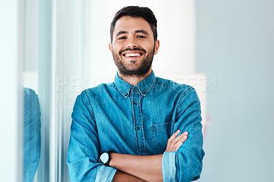 Buy stock photo Cropped portrait of a handsome young businessman smiling while standing with his arms crossed in an office