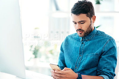 Buy stock photo Cropped shot of a handsome young businessman using a mobile phone while sitting in an office