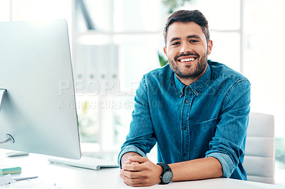 Buy stock photo Cropped portrait of a handsome young businessman smiling while sitting at his desk in an office