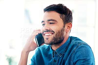 Buy stock photo Cropped shot of a handsome young businessman smiling while taking a phonecall in an office