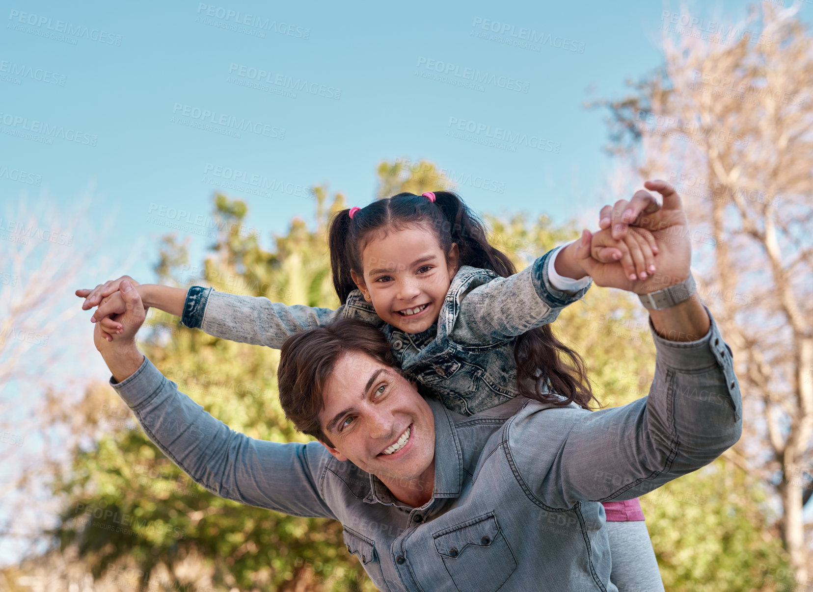 Buy stock photo Shot of an adorable little girl enjoying a piggyback ride with her father at the park