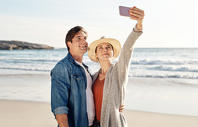 Buy stock photo Young couple, beach selfie and happy in summer sunshine for love, romance or smile for social media post. Man, woman and profile picture for blog, app or internet by ocean, waves or sea for holiday