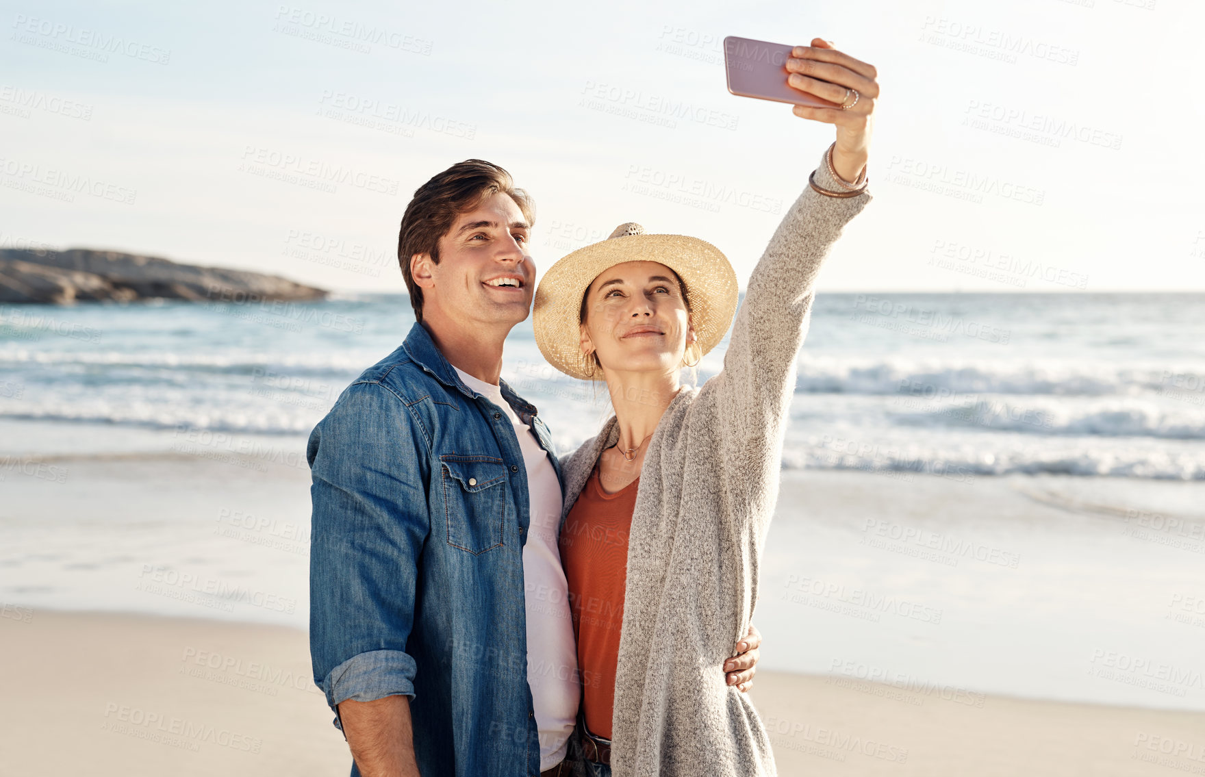 Buy stock photo Young couple, beach selfie and happy in summer sunshine for love, romance or smile for social media post. Man, woman and profile picture for blog, app or internet by ocean, waves or sea for holiday