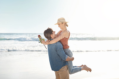 Buy stock photo Couple, lifting and happy at beach with love, rose and travel for vacation by ocean in summer. Man, woman and hug on sea sand with romance, smile and freedom or peace for holiday by water in Greece