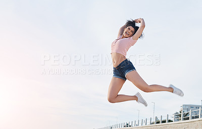 Buy stock photo Shot of a young woman jumping into mid air at the beach