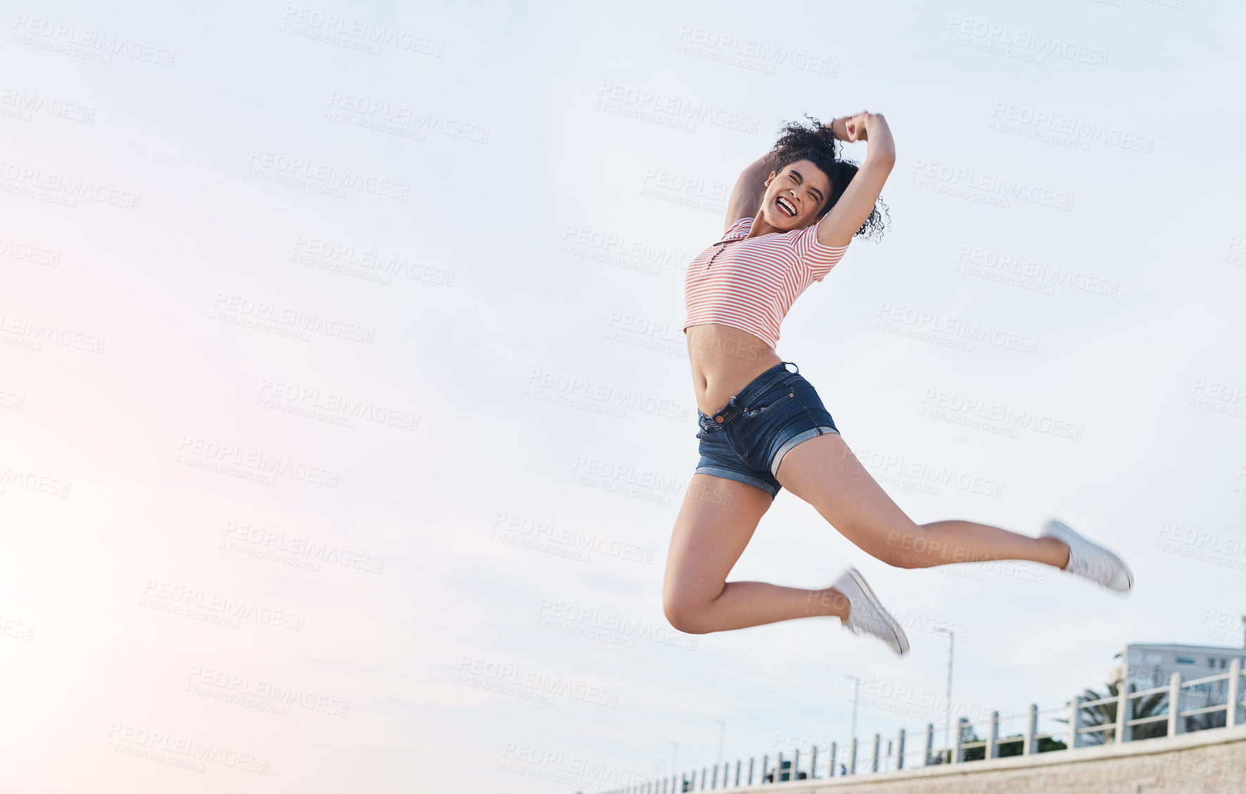 Buy stock photo Shot of a young woman jumping into mid air at the beach