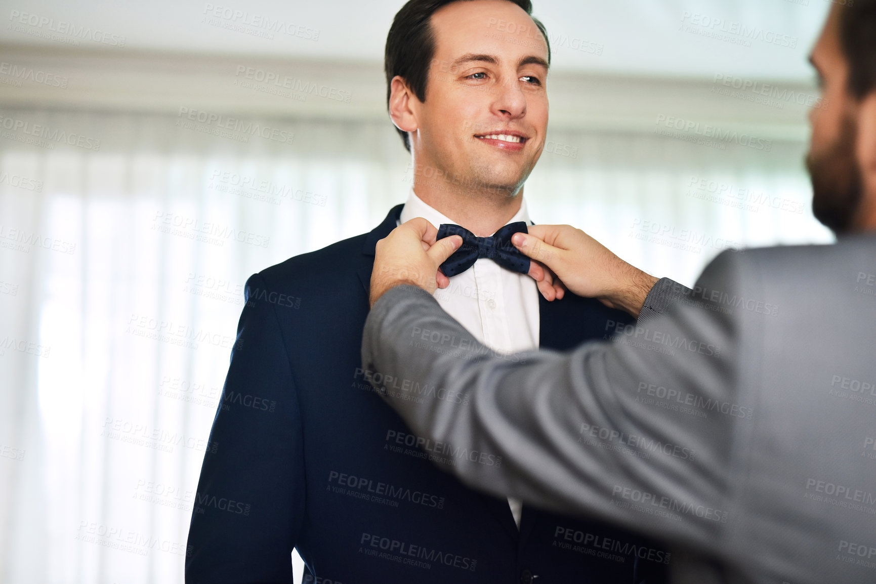 Buy stock photo Shot of an unrecognizable best man helping the bridegroom get dressed on his wedding day