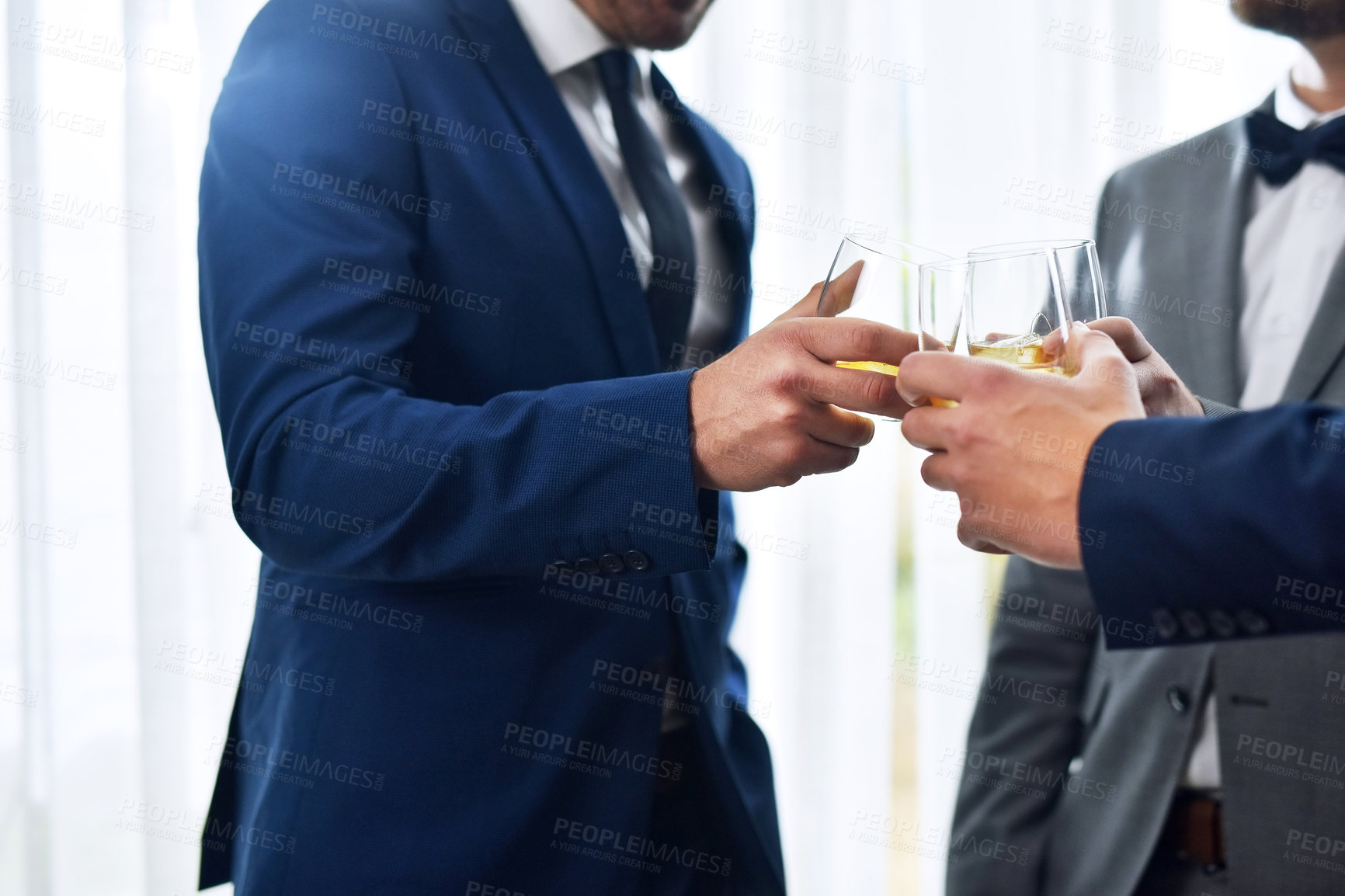 Buy stock photo Shot of two unrecognizable groomsmen sharing a toast with the bridegroom on his wedding day
