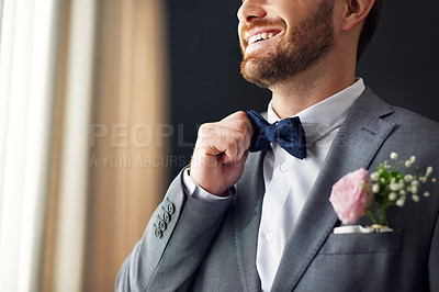 Buy stock photo Shot of an unrecognizable bridegroom adjusting his bowtie inside a changing room on his wedding day