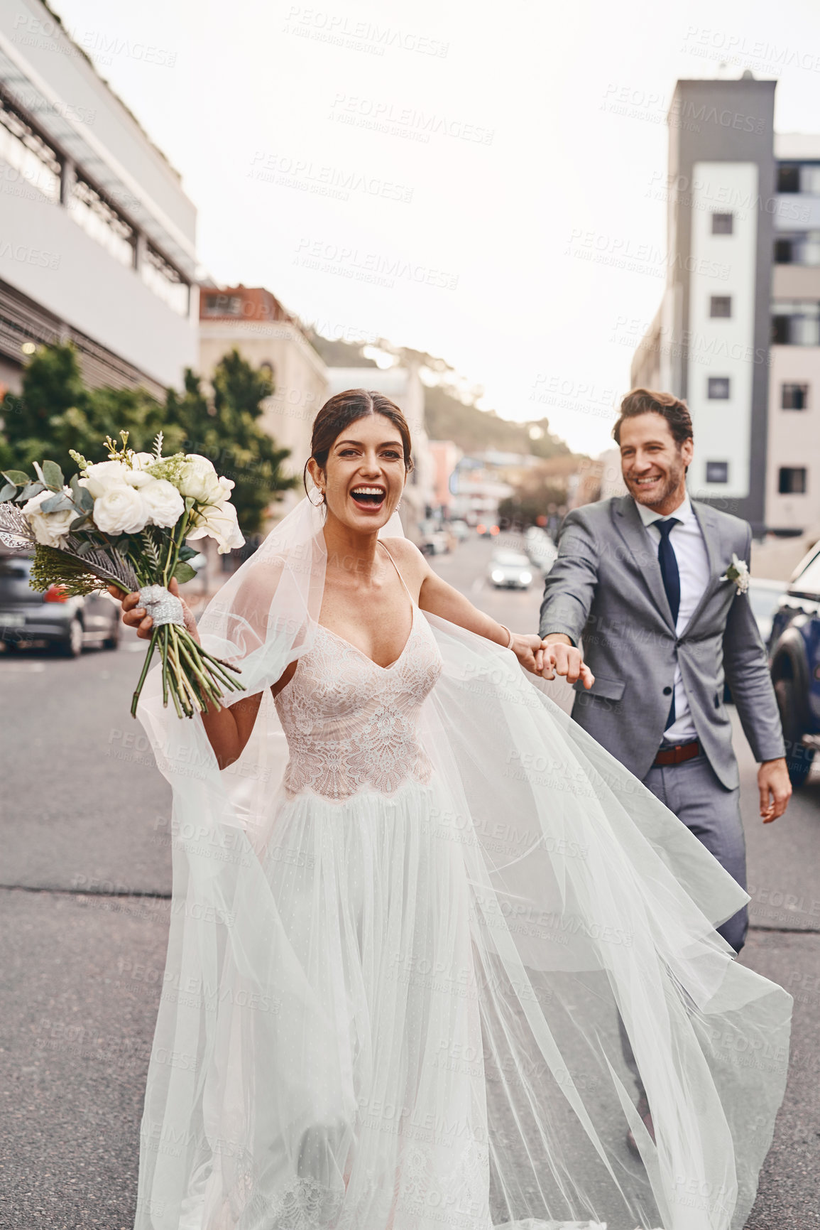 Buy stock photo Wedding, run and a happy couple in a city outdoor together after a ceremony of tradition or love. Flowers, marriage or smile with a man and woman holding hands while running as husband and wife