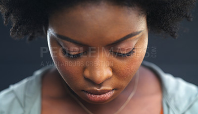 Buy stock photo Cropped shot of a young woman looking down against a dark background