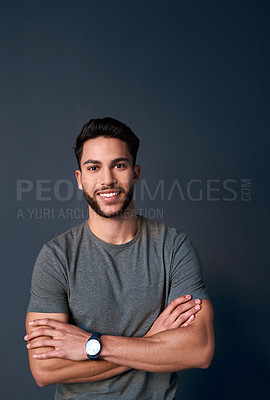 Buy stock photo Cropped portrait of a handsome young businessman standing against a gray background alone with his arms folded