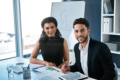 Buy stock photo Cropped portrait of two young businesspeople sitting together in the office and using a tablet and paperwork during a discussion