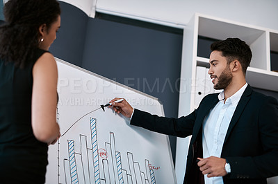 Buy stock photo Cropped shot of a handsome young businessman standing and using a white board to present data to his female colleague