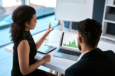 Buy stock photo Cropped shot of two young businesspeople sitting together and having a discussion while using a laptop in the office