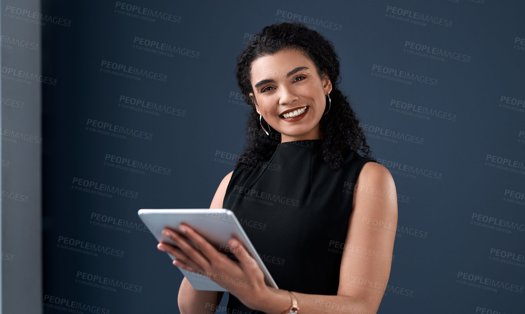 Buy stock photo Cropped portrait of an attractive young businesswoman standing alone and using a tablet against a gray background in the studio