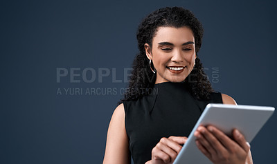 Buy stock photo Cropped shot of an attractive young businesswoman standing alone and using a tablet against a gray background in the studio