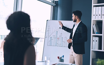 Buy stock photo Cropped shot of a handsome young businessman standing and using a white board to present data to his female colleague