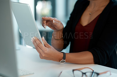Buy stock photo Cropped shot of an unrecognizable businesswoman sitting alone and using a tablet in her office