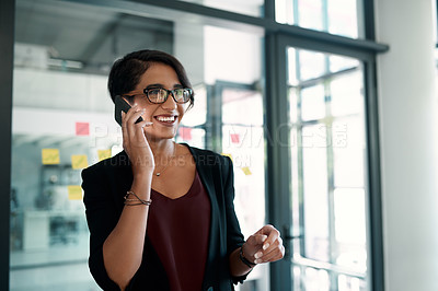 Buy stock photo Cropped shot of an attractive young businesswoman standing in her office alone and talking on her cellphone