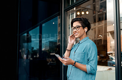 Buy stock photo Cropped shot of an attractive woman standing outside and putting her earpods in to listen to music through her cellphone
