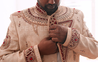 Buy stock photo Cropped shot of an unrecognizable bridegroom fastening his attire while getting dressed on his wedding day