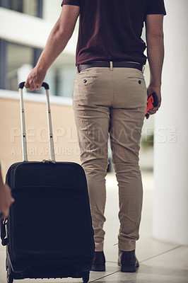 Buy stock photo Rearview shot of an unrecognizable man carrying his luggage in an airport